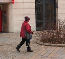 nitra, slovaquie - 01.06.2023 une femme mûre avec des bâtons de marche nordique se promène dans les rues de la ville. le concept d'un mode de vie sain. photo