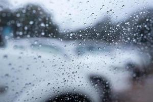 des gouttes de pluie bruine sur le pare-brise en verre le soir. rue sous une pluie battante. feu arrière bokeh. mise au point douce. veuillez conduire prudemment, route glissante. mise au point douce. photo