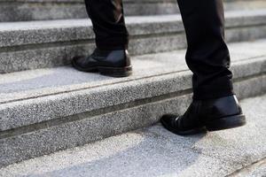 homme d'affaires moderne travaillant les jambes en gros plan en montant les escaliers dans la ville moderne. à l'heure de pointe pour travailler photo