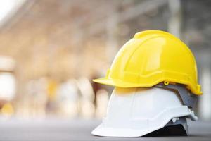 chapeau de casque de sécurité dur jaune et blanc dans le projet sur le chantier de construction sur sol en béton sur la ville avec la lumière du soleil. casque pour ouvrier comme ingénieur ou ouvrier. concept de sécurité d'abord. photo