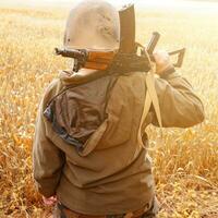 un soldat avec une mitrailleuse se tient dans un champ, des champs de blé ukrainiens et la guerre. photo
