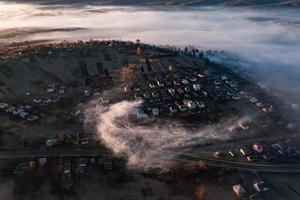 le village est plus haut que les autres, il y a du brouillard et des nuages autour du village, l'aube dans la zone ukrainienne. photo
