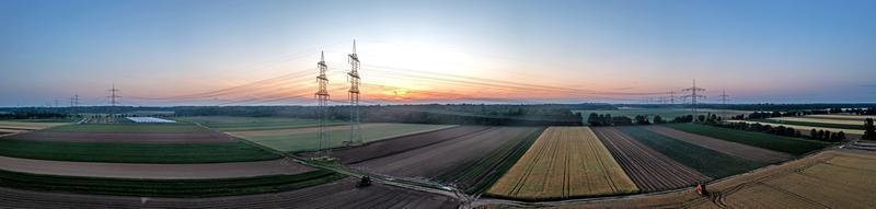 image panoramique de la ligne électrique au-dessus de la terre pendant le coucher du soleil dans la rémanence photo