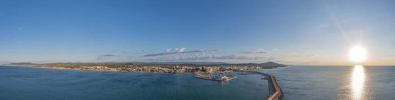 panorama de drone de la ville espagnole de vinaros avec le grand brise-lames à l'entrée du port pendant le lever du soleil photo