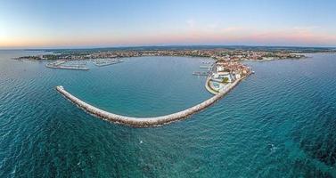 panorama de drone de la ville côtière croate umag prise pendant le coucher du soleil au-dessus de l'entrée du port avec brise-lames photo