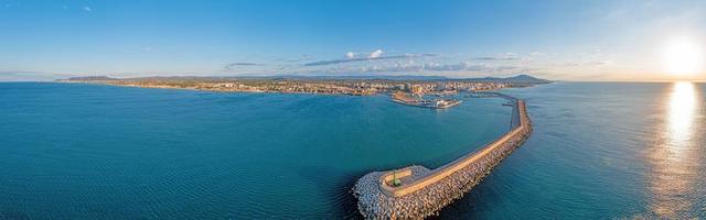 panorama de drone de la ville espagnole de vinaros avec le grand brise-lames à l'entrée du port pendant le lever du soleil photo