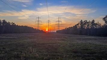 Poteaux électriques rétroéclairés photographiés au coucher du soleil en zone rurale photo