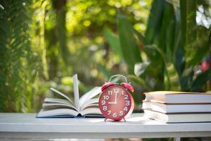 Réveil rouge avec livre sur fond de jardin nature photo