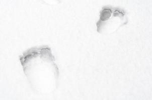 Empreintes de pieds humains nus sur la neige blanche se bouchent photo