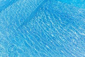 une belle eau de piscine avec un soleil relaxant scintille à la surface. vacances d'été ou concept de vacances, texture de piscine photo