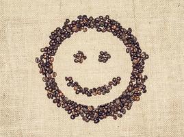 visage souriant formé par des grains de café sur un tissu grossier photo