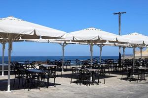 chaise et table dans un café dans un parc de la ville près de la mer. photo