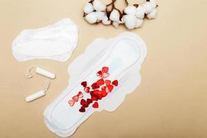 serviettes hygiéniques pour femmes avec tampons, coton fleuri sur fond beige avec coeurs rouges photo