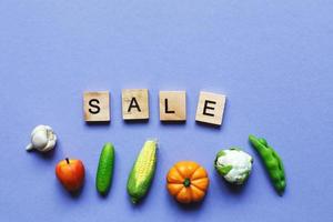 vente d'inscription avec des légumes et des fruits sur fond violet. photo