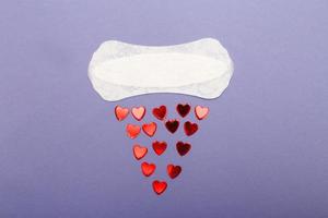 tampon d'hygiène quotidienne pour femmes sur fond violet avec coeurs rouges photo