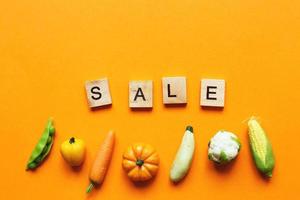 vente d'inscription avec des légumes et des fruits sur fond orange. photo