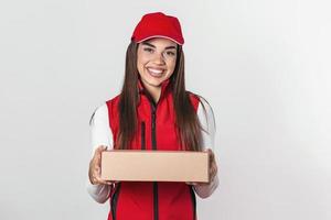 image d'une jeune femme de livraison heureuse en bonnet rouge debout avec une boîte postale de colis isolée sur fond blanc. photo