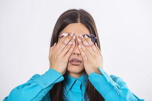 jeune femme à lunettes se frotte les yeux, souffrant d'yeux fatigués, concept de maladies oculaires. femme à lunettes couvrant les yeux du visage à l'aide de ses deux mains isolées sur fond photo