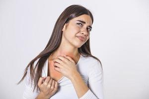 jeune femme se grattant le cou à cause de démangeaisons sur fond gris. la femelle a un cou qui démange. le concept des symptômes d'allergie et des soins de santé photo