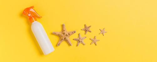 bouteilles de crème solaire avec coquillages sur la vue de dessus de table jaune photo