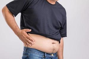 douleur corporelle, douleur à la hanche ou effet d'un problème de foie gros homme utilisant sa main et appuyant sur la position de la hanche. tourné en studio sur gris photo