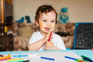 un enfant joyeux et joyeux dessine avec un stylo feutre dans un album en utilisant une variété d'outils de dessin. photo