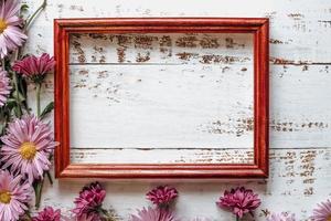 les chrysanthèmes roses sont placés sur un fond en bois blanc avec un espace pour le texte et un cadre photo