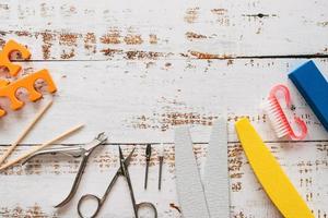 limes à ongles, ciseaux, pinces, paillettes et vernis à ongles sur un fond en bois blanc. avec un espace pour votre texte photo