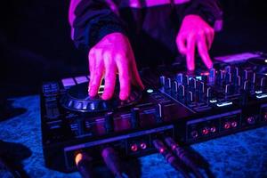 console dj pour mixer de la musique avec les mains et avec des personnes floues dansant lors d'une soirée en boîte de nuit photo