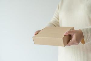 mains de femme portant une boîte en carton marron. concept d'utilisation d'une boîte de papier recyclé. photo