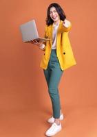 photo pleine longueur d'une jeune femme asiatique utilisant un ordinateur portable sur fond