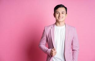 portrait de jeune homme asiatique portant un costume rose posant sur fond photo