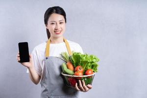 jeune femme asiatique tenant des légumes sur fond photo