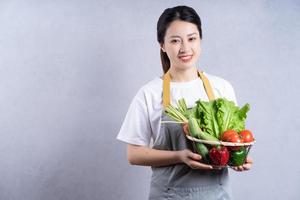 jeune femme asiatique tenant des légumes sur fond photo