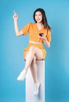 photo pleine longueur d'une jeune femme asiatique utilisant un smartphone sur fond bleu