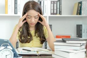 une étudiante asiatique a de l'anxiété à cause des examens, les femmes se préparent aux tests et apprennent les leçons à la bibliothèque. stress, désespoir, hâte, incompréhension lecture, découragement, attente, connaissance photo