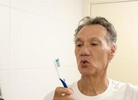 Senior man looking at his old usé notre brosse à dents photo