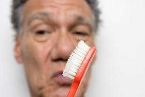 Senior man looking at his old usé notre brosse à dents photo