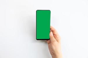 Femme tenant un téléphone mobile à écran vert avec un fond blanc photo