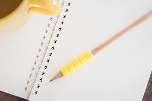 crayon jaune et tasse sur un bloc-notes photo