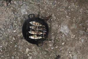 le processus de fabrication du poisson grillé qui est brûlé sur des charbons de noix de coco photo