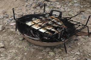 le processus de fabrication du poisson grillé qui est brûlé sur des charbons de noix de coco photo