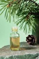 huile essentielle de pin en bouteille de verre sur granit de pierre grise sur vert menthe. orientation verticale. photo