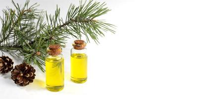 bannière publicitaire avec de l'huile essentielle de pin dans de petites bouteilles en verre avec branche et cônes sur blanc avec espace de copie. photo