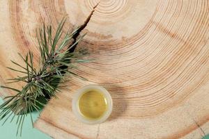 concept d'aromathérapie naturelle et de spa - petit pot en verre d'huile essentielle de pin, branche, scie en bois coupée avec anneaux annuels. photo