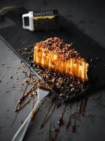 Tranche de gâteau au fromage au caramel sur une plaque noire photo