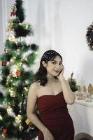 portrait d'une jolie jeune fille vêtue d'une robe rouge, souriant à la caméra, debout dans un salon de noël décoré à l'intérieur photo