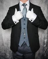 portrait d'un majordome ou d'un concierge élégant en costume gris foncé et gants blancs se tenant fièrement. concept d'industrie de service et de courtoisie professionnelle. photo