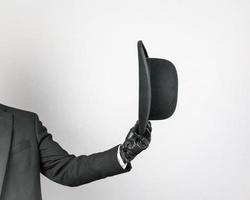 image isolée d'un homme en costume sombre et gants en cuir qui retire poliment le chapeau melon. majordome britannique classique ou homme d'affaires britannique. photo