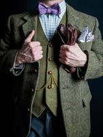 portrait d'un gentleman britannique en costume de tweed tenant des gants en cuir et se tenant fièrement sur fond noir. style vintage et mode rétro. photo